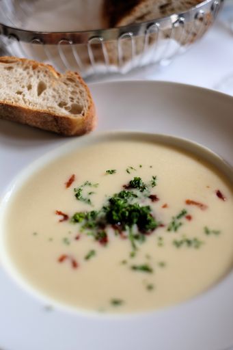 A high angle shot of delicious creamy soup with bread on the side