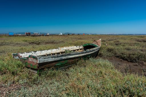 A shot of an old boat in the middle of a meadow in Cais Palafítico da Carrasqueira, Portugal