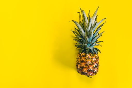 A fresh pineapple fruit on a yellow background with space for your text
