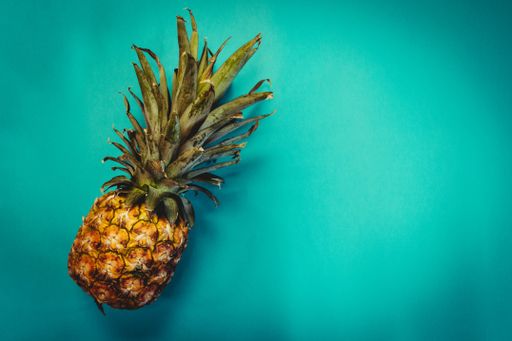 A tilted fresh pineapple fruit on a green background with space for your text