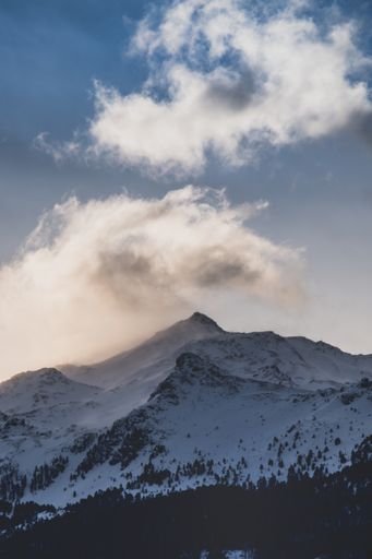 A vertical shot of the snowy peaks of the mountains under the cloudy sky
