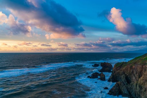 A serene sunset over cliffs and blue waters. Mussel Rock Park, Daly City, California