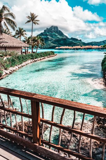 A tropical paradise with turquoise waters, palm trees, and mountains. Bora Bora, French Polynesia