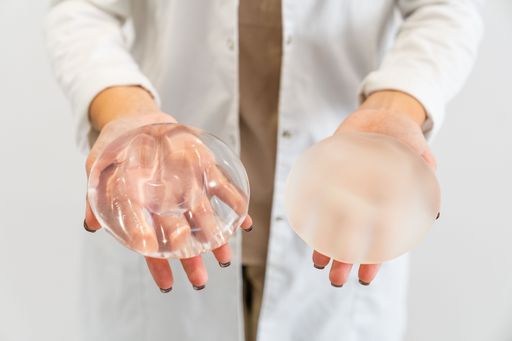 The Doctor's hands holding two different types of breast prostheses.