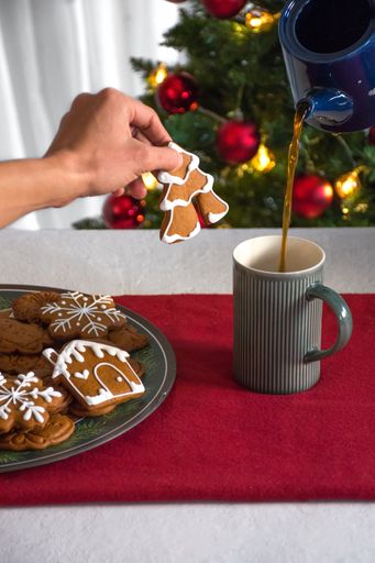 A person pouring freshly brewed coffee over a plate of sweet, crunchy cookies