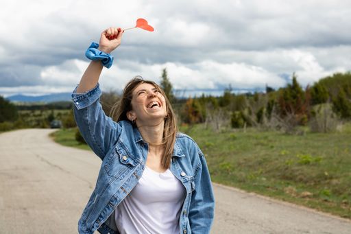 A cute happy Caucasian female walking with a heart-shaped lollipop in her hand