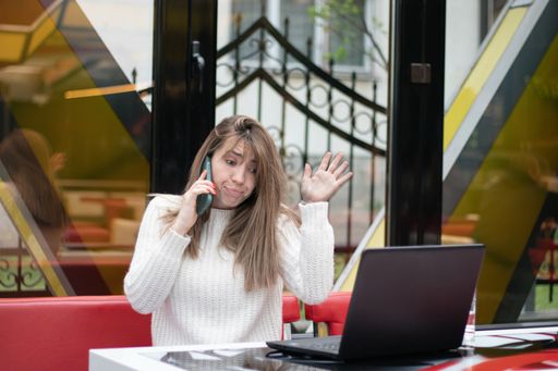 A closeup shot of a Caucasian female talking via phone and working in a cafe