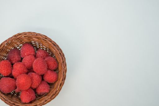 A small basket with fresh raspberries isolated on a whitebackground