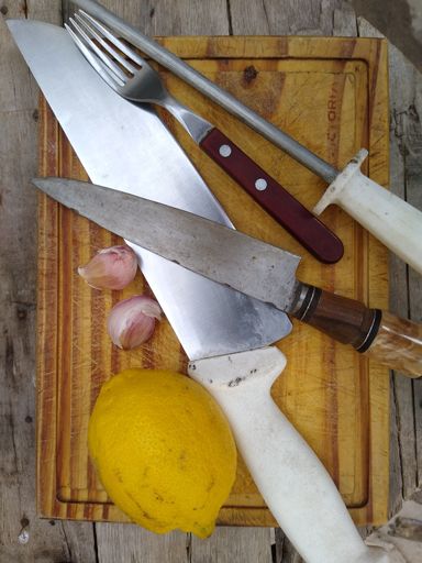 A vertical shot of lemon on kitchen board with knives and fork