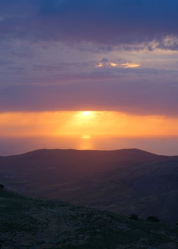 A vertical shot of a landscape with mountain silhouette and beautiful skyline