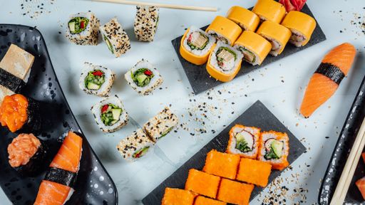 A top view of platters full of delicious sushi on a white surface
