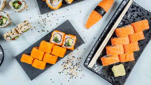 A top view of platters full of delicious sushi on a white surface