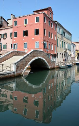 A vertical shot of a stone bridge and colorful buildings in Venice, Italy