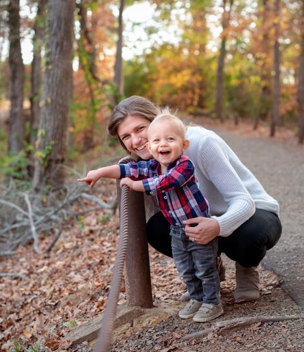 A happy little toddler and his mother hugging and smiling at the camera in the forest in Texas