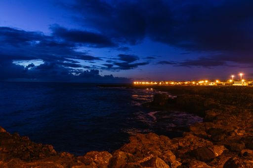 A beautiful scenery of the rocky seashore under the cloudy dark night sky