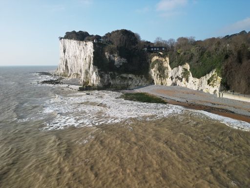 An aerial shot of a tranquil beach on a sunny day, with crystal-clear water