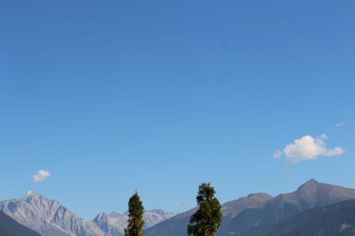 A small airplane soars through the sky surrounded by a majestic mountain range, providing a unique and thrilling perspective of nature