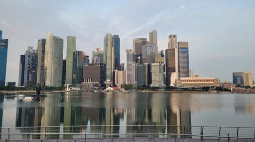 A skyline of high-rise buildings illuminated against a backdrop of tranquil blue water, depicting the hustle and bustle of an urban metropolis