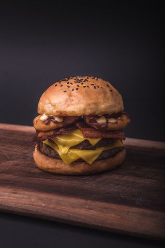 A vertical shof a fresh double cheeseburger with sauce on a wooden board