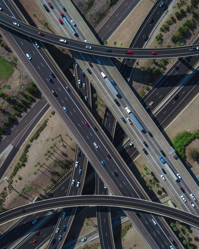 An overhead drone shot of a busy highway intersection full of traffic during daytime