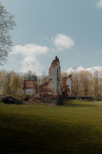 A vertical shot of an old abandoned brick building on the meadow