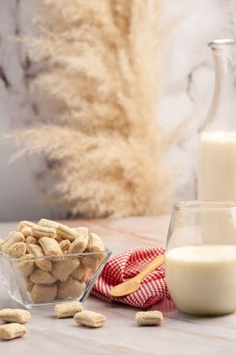 A vertical closeup shot of a gourmet bowl of cereal and a bottle and glass of milk on a kitchen table