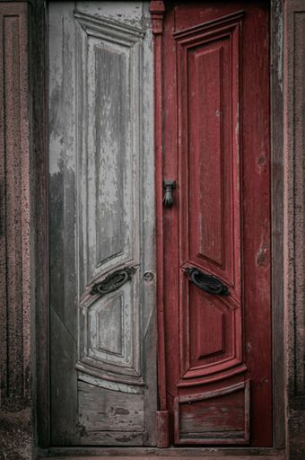 A vertical shot of an old white and red door during daylight