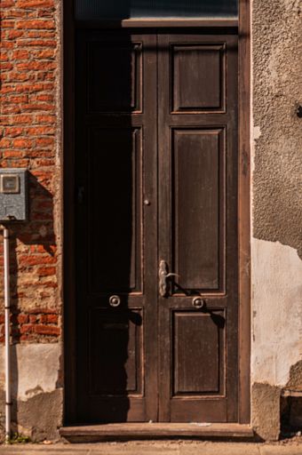 A vertical shot of an old brown door during daylight