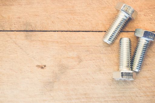 A top view of long silver bolts on a wooden surface
