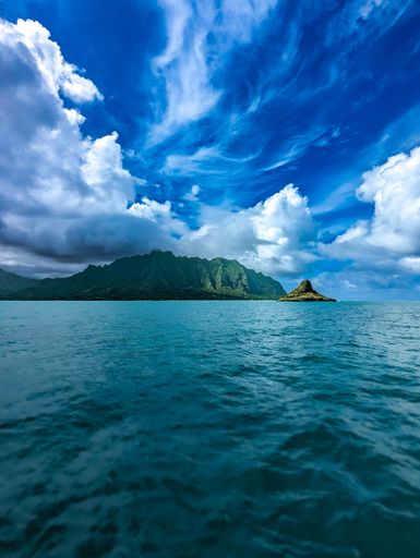 An aerial view of a tropical island with multiple smaller islands in the distance and a mountain range in the background