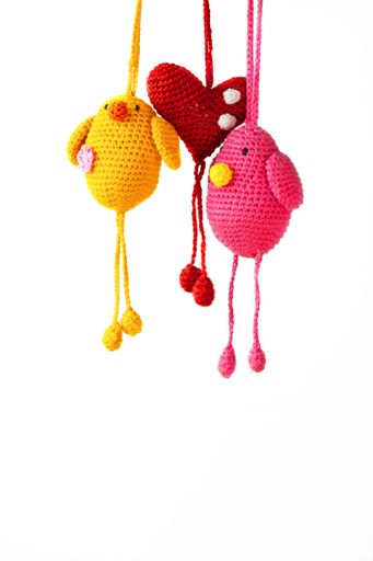 A vertical shot of two birds and heart amigurumi patterns hanging on white background