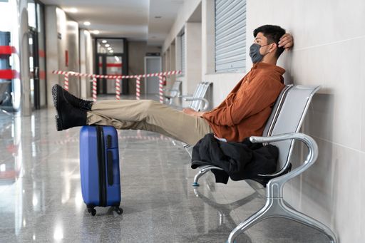 A closeup of a person in a facial mask at the airport waiting for his flight - a new normal concept