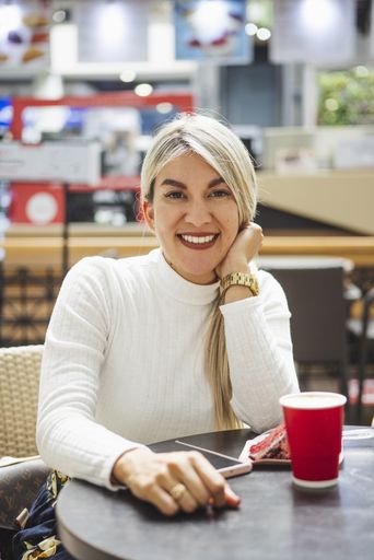 A vertical shot of a blonde Hispanic female sitting in a cafe
