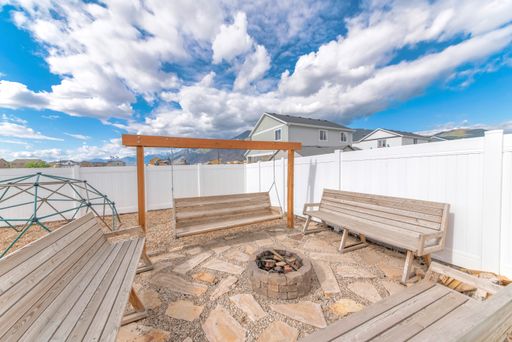 A beautiful sunny backyard idea with wooden benches and a swing with a fire pit in the middle