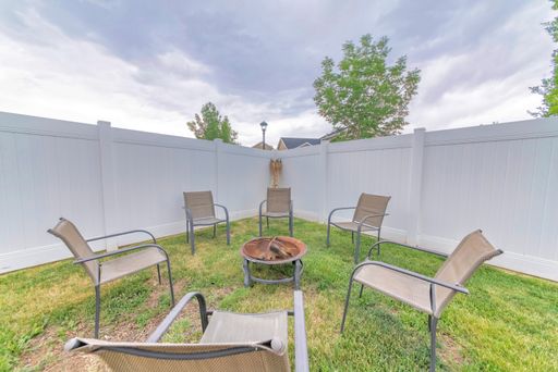 A beautiful sunny backyard with chairs and a fire pit in the middle