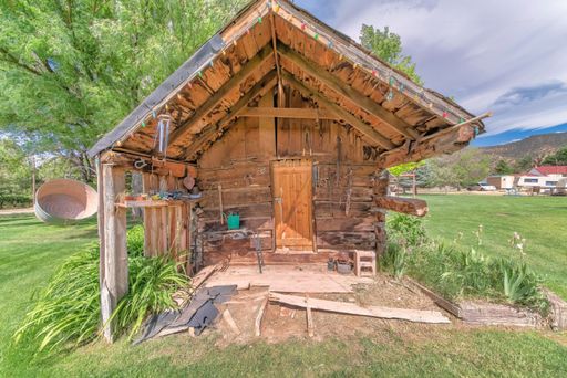 A weathered wooden shed in the middle of fresh green grass field