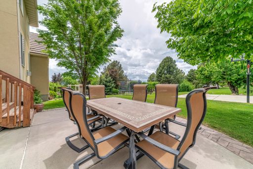 A beautiful sunny backyard with a wooden table and chairs on background of fresh green trees
