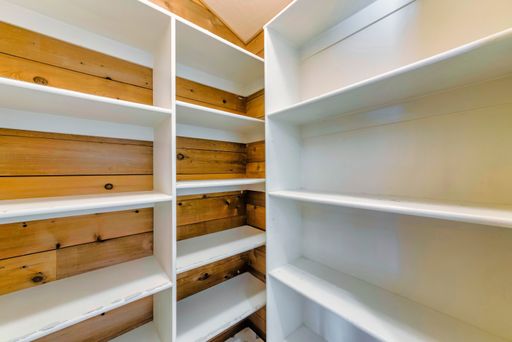 A minimalistic pantry interior design with wooden empty racks in white color