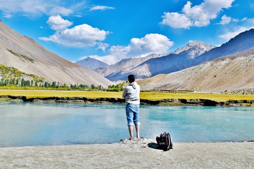 A closeup shot of a young male standing on a mountainous lake shore
