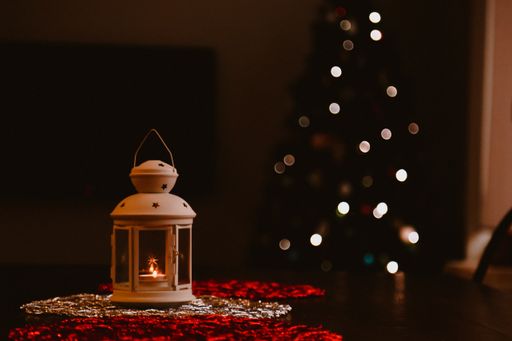 A closeup shot of a candle holder and Christmas tree with bokeh lights effect