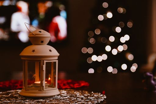 A closeup shot of a candle holder and Christmas tree with bokeh lights effect
