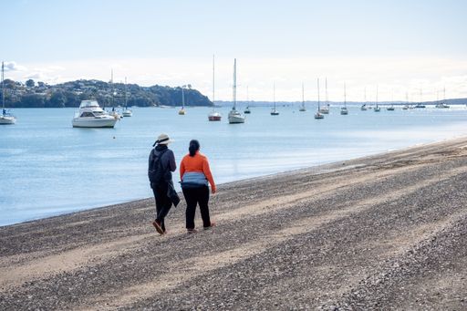 Two women walking along Bucklands beach. Auckland, New Zealand - May 13, 2021