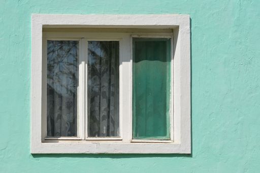 A close-up shot of a window on a cyan wall