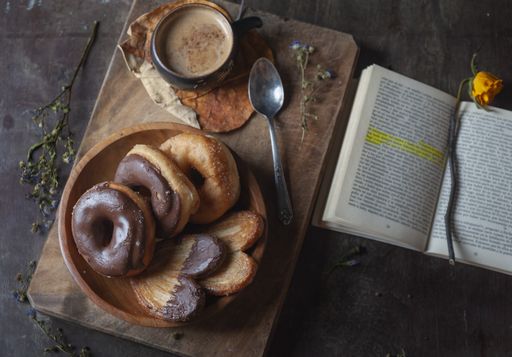 A relaxing rustic scene with a marked book, a plate of donuts and a cup of hot coffee