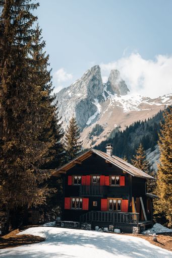 A beautiful shot of a typical Swiss chalet near snowy mountains in Taney, Switzerland