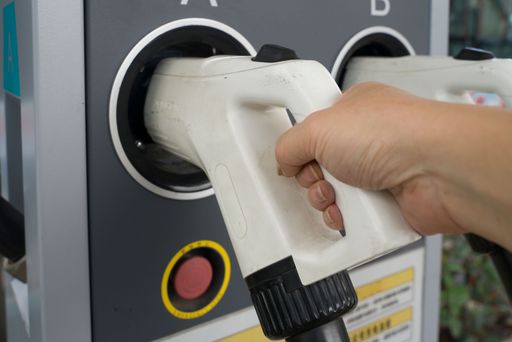 close up view of driver recharging ev car with hand holding the plug. sustainable energy concept.