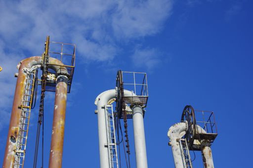 A low angle shot of an industrial plant with a net of pipes on a sunny day
