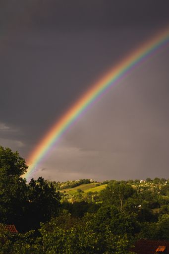 A beautiful view of a rainbow in the gloomy sky after the rain over the field