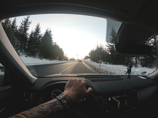 A long shot of a road cleared of snow. Captured from inside a car