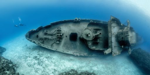 Scuba divers examining the famous USS Kittiwake submarine wreck in the Grand Cayman Islands